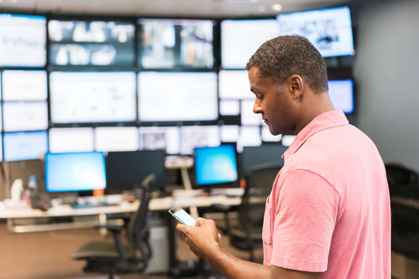 Technician looking at his cellphone in a server room monitoring